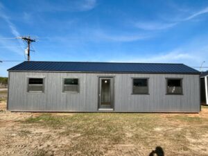 Gray 40-foot portable building with wood siding, dark metal roof, four windows, and a centered glass entry door