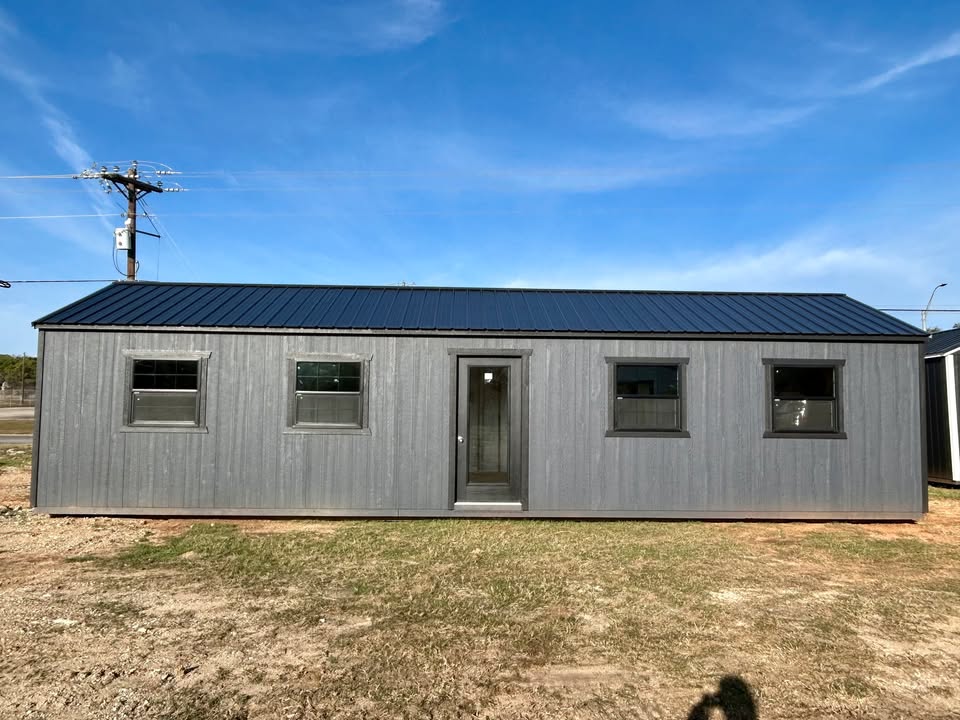 Gray 40-foot portable building with wood siding, dark metal roof, four windows, and a centered glass entry door