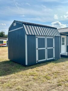 Blue lofted barn-style portable shed with wood siding, gray trim, and double entry doors