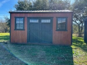 Front exterior view of an A-frame style portable shed with wood siding, double doors, and two front windows