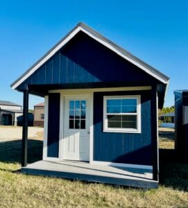 Front exterior view of a blue portable cabin-style shed with covered porch, single entry door, and front window