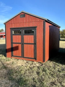 Red barn-style portable shed with wood siding, black trim, and double doors with windows