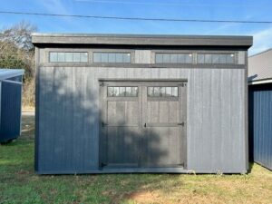 Front exterior view of a modern-style portable shed with wood siding, double doors, and upper transom windows